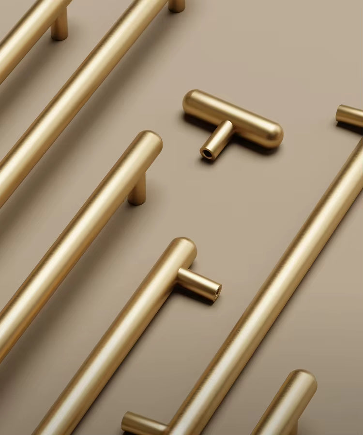Gold cabinet handles arranged on a beige background